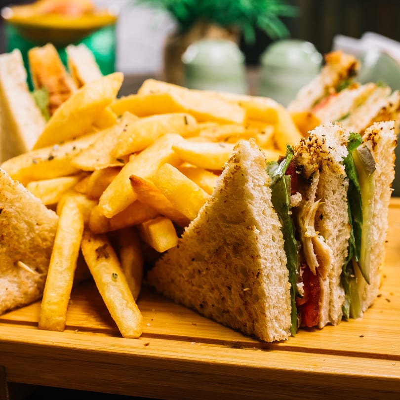 Club sandwiches with chicken, lettuce, and tomato, served with a pile of golden french fries.